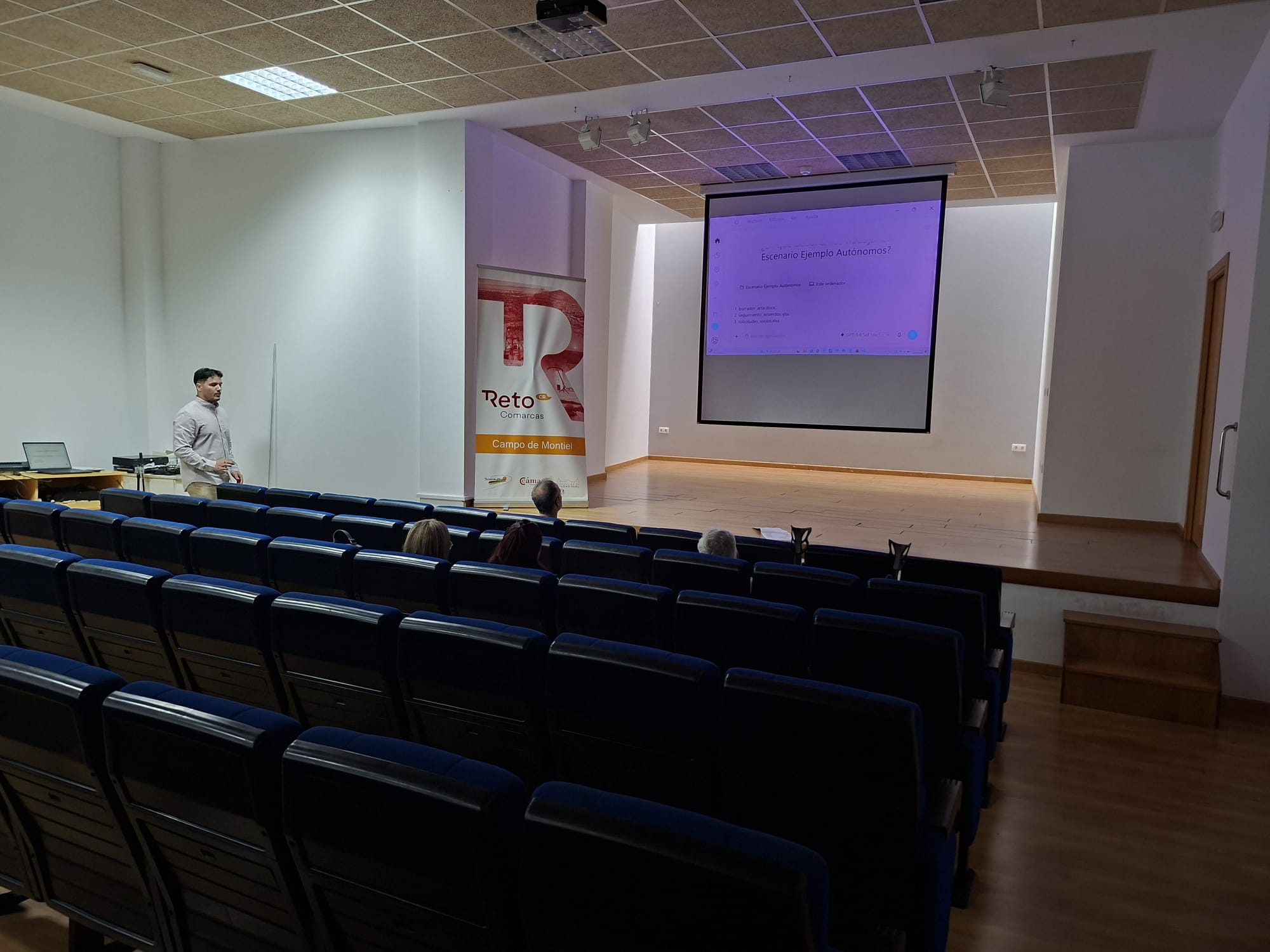 Sesión de IA útil de Reto Comarcas, con ponente, asistentes y pantalla de proyección.